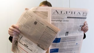 Ein Mann liest eine Zeitung mit Stelleninseraten.