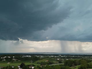 Aus dunkle Gewitterwolken über dem See fällt Regen. 