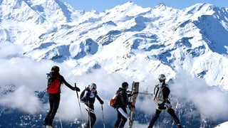 Drei Skifahrer vor Bergkulisse stehend