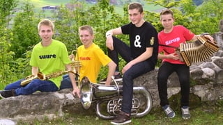 Vier junge Musikanten auf einer Mauer.