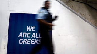 Ein Mann geht an einem Schild vorbei, auf dem steht "we are all greeks", "wir sind alle Griechen". Ein Mann geht an einem Schild vorbei, auf dem steht "we are all greeks", "wir sind alle Griechen".