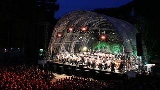 Orchester spielt bei Nacht auf einer Openair-Bühne