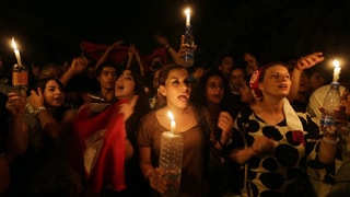 Demonstrierende Regierungsgegner in der Nacht mit Kerzen in der Hand.