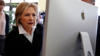 Clinton mit gerunzelten Augenbrauen und leicht vorgebeugt an einem grossen Bildschirm sitzend.