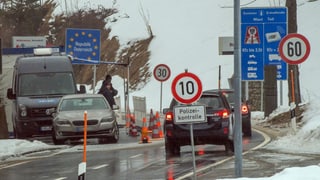 Polizisten kontrollieren Fahrzeuge an der Grenze.