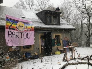Provisorische Hütten aus Holz und Blachen im Schnee und ein Haus.