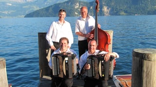 Zwei Akkordeonisten, ein Bassgeiger und ein weiterer Musikant posieren fürs Gruppenbild auf einem Schiffssteg.