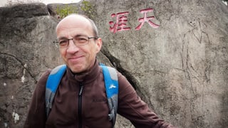 Ein Mann steht vor einem Stein mit chinesischen Schriftzeichen und einem Porträt einer Frau Ein Mann steht vor einem Stein mit chinesischen Schriftzeichen und einem Porträt einer Frau