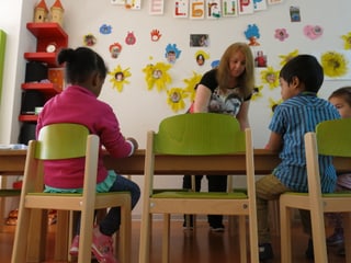 Kindern aus verschiedenen Ländern in der Spielgruppe am Tisch.