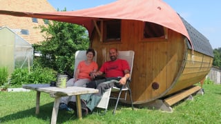 Ein Paar sitzt vor einem Fass mit Fenstern. Ein Paar sitzt vor einem Fass mit Fenstern.