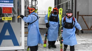Chinesen steigen in Schutzanzüge eingehüllt vom Skilift. Chinesen steigen in Schutzanzüge eingehüllt vom Skilift.