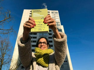 Annette König hält den Roman «Null Komma Irgendwas» von Lavinia Braniște in die Luft. Im Hintergrund ein Hochhaus, das dem auf dem Buchcover gleicht.