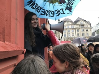 Eine junge Frau mit Megaphon und Schirm.