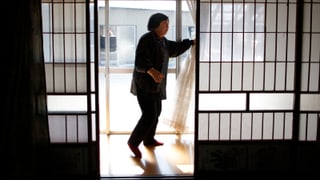 Eine japanische Frau zieht Vorhänge zur Seite