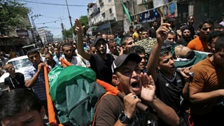 Palästinenser ziehen demonstrierend durch eine Strasse in Gaza. 