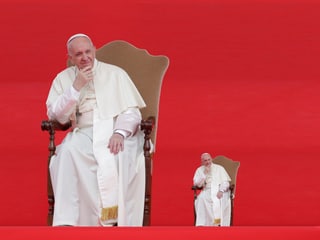 Papst Franziskus sitzt auf einem Stuhl, einmal in Gross, einmal in Klein.