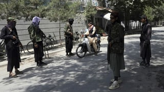 Bewaffnete Taliban lassen eine Motorradfahrer passieren