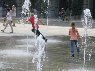 Kinder rennen durch Wasserfontänen