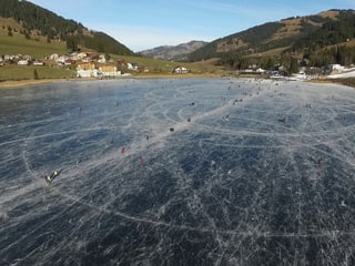 Gefrorener See mit Schlittschuhfahrern.