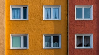 Blick auf eine gelbe Hauswand eines Wohnblocks. Zwei Stockwerke und 6 Fenster sind sichtbar. Blick auf eine gelbe Hauswand eines Wohnblocks. Zwei Stockwerke und 6 Fenster sind sichtbar.