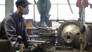 Ein Fabrikarbeiter an einer Maschine.