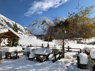 Viel Neuschnee auf Tischen und Bänken, der an der Herbstsonne langsam schmilzt.