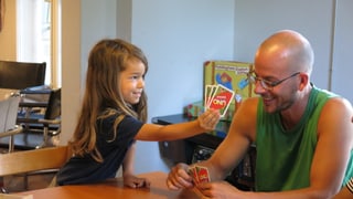 Kleiner Junge spielt Uno mit Lernbegleiter Gregor Engel
