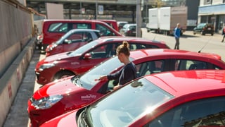 Sechs rote Autos stehen nebeneinander auf einem Parkplatz.
