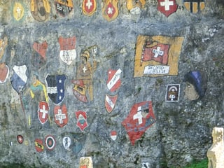 Man sieht eine Felswand mit verschiedenen Schweizer Kantonswappen. Die Wand ist im Chessiloch bei Grellingen.