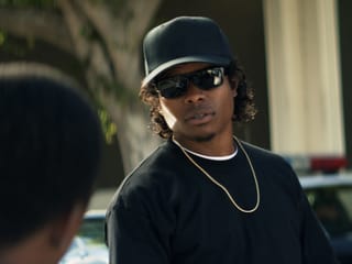 Eazy-E (Jason Mitchell) mit Goldkette, dunklem Cap und schwarzer Sonnenbrille.