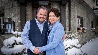 eine Frau und ein Mann stehen vor einem Hoteleingang im Schnee