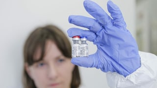Eine Frau hält zwei Fläschchen mit Impfstoff in die Kamera.