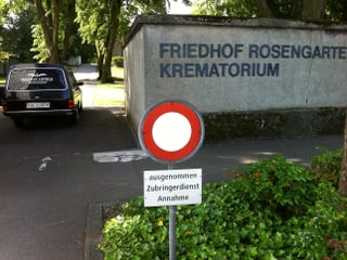 Der Eingang zum Freidhof Rosengarten. In der Einfahrt steht der Leichenwagen des "Bestattungsinstitut Conrad".