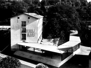 Schwarzweissbild: Längliches, schmuckloses Gebäude mit der Aufschrift "Hotel Volkshaus".