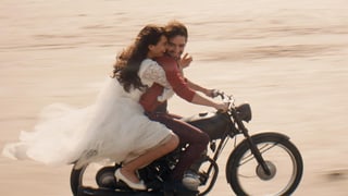 Frau im Brautkleid mit Mann auf Motorrad
