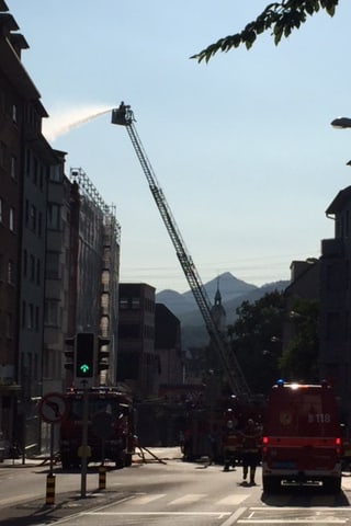 Ein Feuerwehrkran löscht Feuer an einem hohen Gebäude.