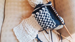 Ein begonnenes Strickwerk liegt auf einem Sessel. Ein begonnenes Strickwerk liegt auf einem Sessel.