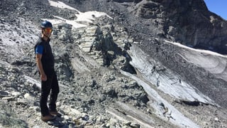 Ein Mann mit Helm und Sonnenbrille in einer Berglandschaft