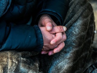 Verschränkte Hände eines Mannes, der auf dem Boden sitzt Verschränkte Hände eines Mannes, der auf dem Boden sitzt