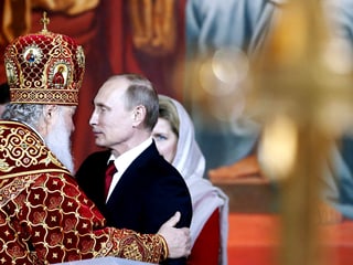 Präsident Putin wird von einem orthodoxen Patriarchen umarmt.