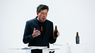 Ein Mann mit einer Bierflasche steht an einem Stehtisch.