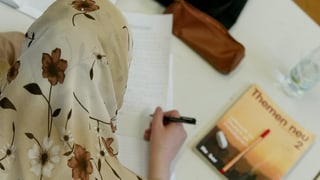 Ein muslimisches Mädchen mit Kopftuch beim Schreiben. 