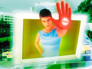 Symbolbild: Frau streckt ihre Hand aus Computerbild und signalisiert Stop.