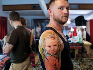 Mann mit Kind am Oberarm-Tattoo