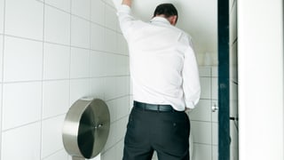 Ein Mann pinkelt im Stehen Ein Mann pinkelt im Stehen