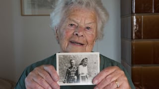 Ältere Frau hält lächelnd ein Schwarz-Weiss-Foto in der Hand