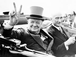 Winston Churchill (linke Seite) mit Zylinder in Auto sitzend, Victory-Zeichen machend. Neben ihm sitzt Robert Schuman