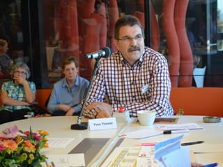 Yves Thomet vor dem Mikrofon, im Hintergrund zwei Frauen aus dem Publikum.