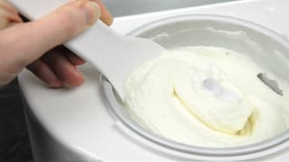Eine Person schöpft Glace aus einer Eismaschine.