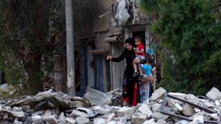 Eine junge Frau klettert mit zwei Kindern über Feld mit Schutt. Eine junge Frau klettert mit zwei Kindern über Feld mit Schutt.
